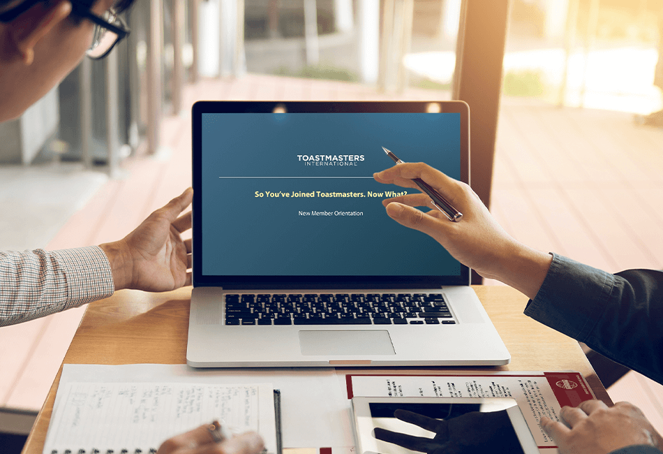 Photo of Toastmasters members reviewing the New Member Orientation PowerPoint on a laptop