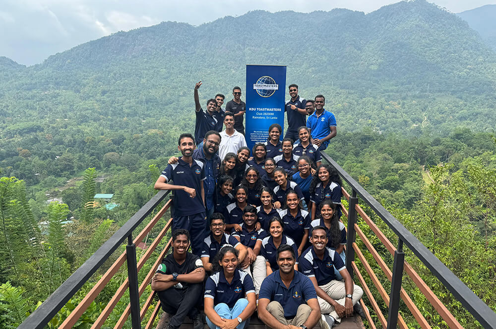 Group of people posing in foreground of mountains and trees with blue banner