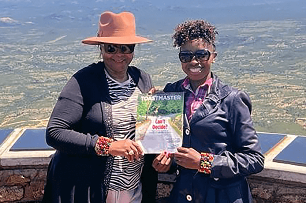 Two women posing with the Toastmaster magazine at a site in Zimbabwe