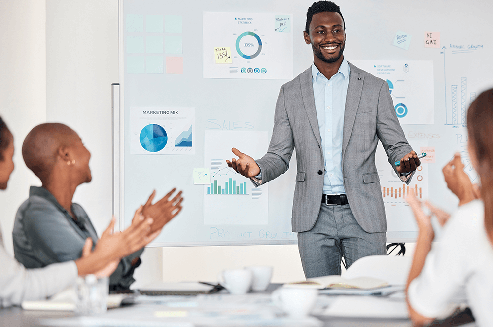 Man smiling with arms raised in front of graphs