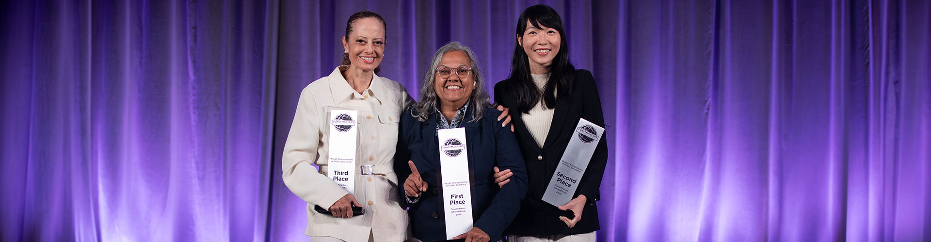 Three women standing and holding trophies