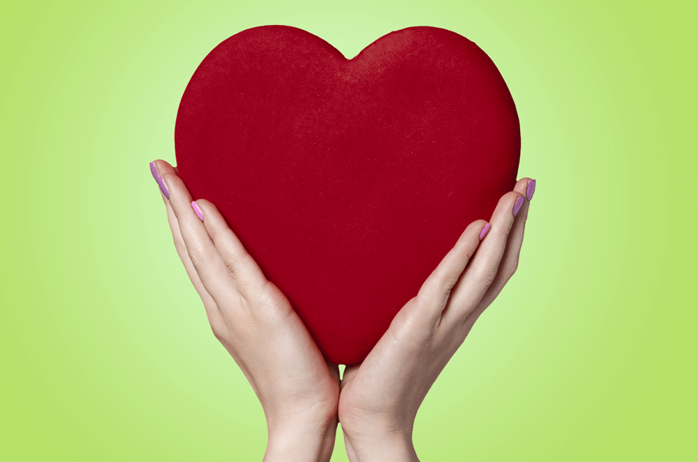 Two hands holding a red heart