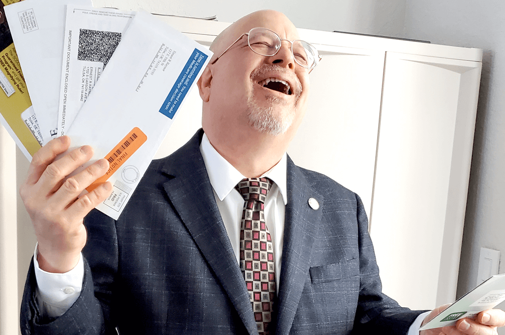 Man in suit laughing and holding mail