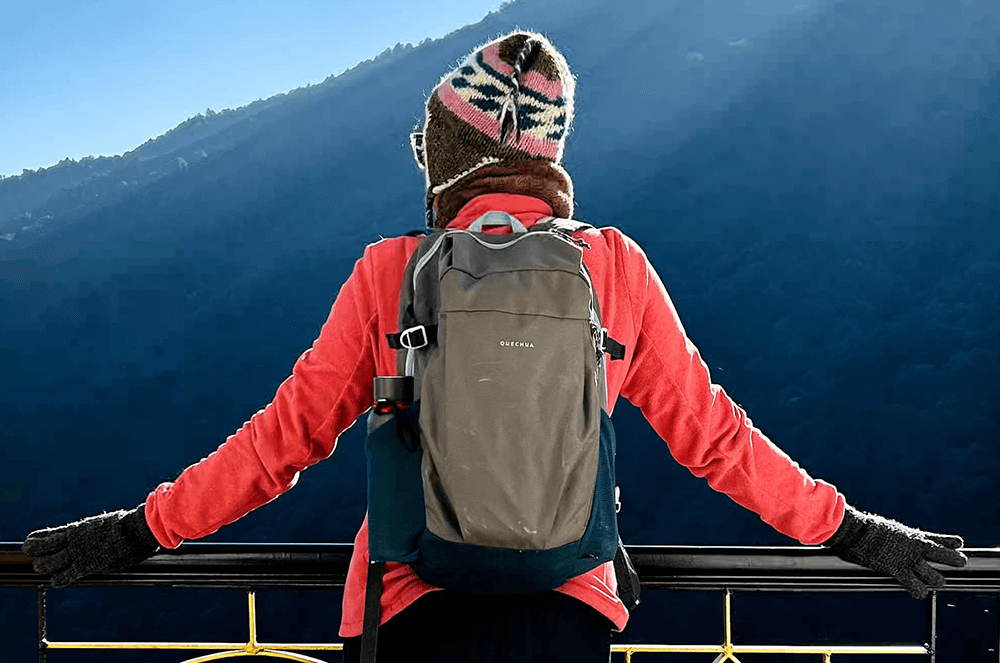 Woman carrying a backpack standing by a mountain