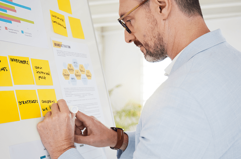 Man writing on a whiteboard with sticky notes