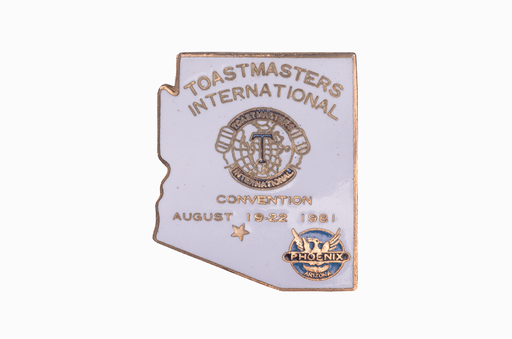 A pin in the shape of Arizona with Toastmasters International across the top