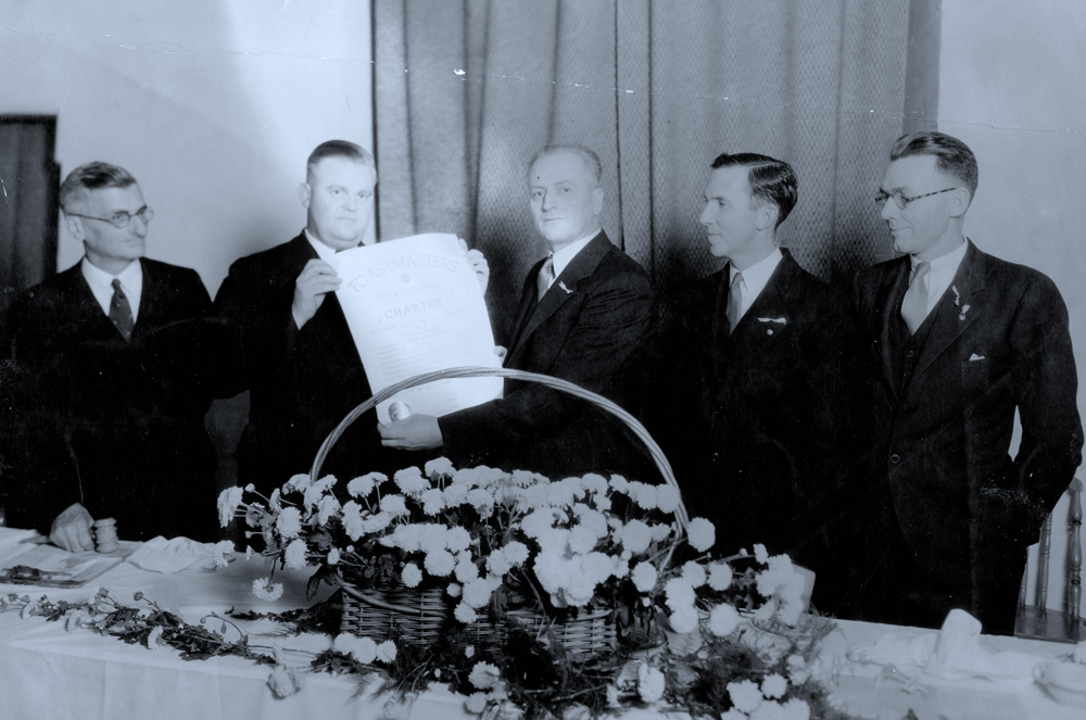 The second Toastmasters club, the Anaheim Toastmasters Club, receives its charter, in 1925, with Ralph Smedley looking on.