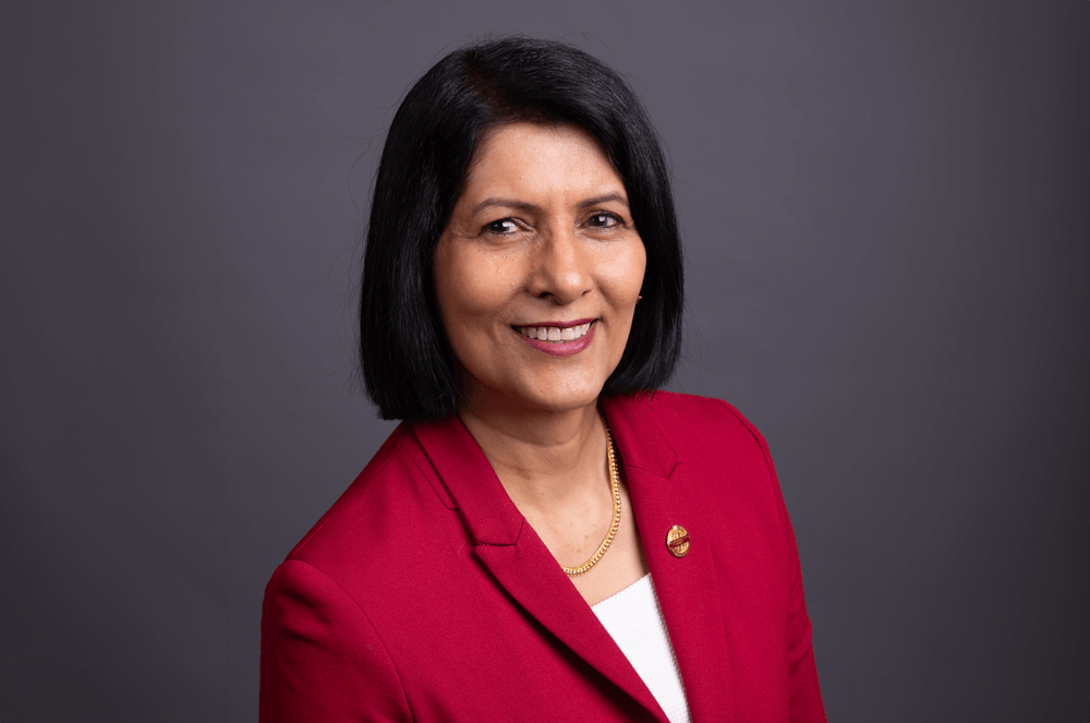 Toastmasters International President Radhi Spear in red suit jacket with Toastmasters pin