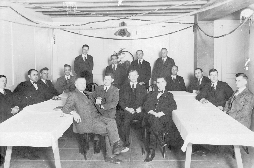 Black and white photo of group of men posing in basement