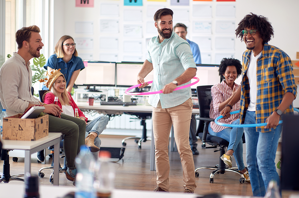 Colleagues watching two men hula hoop at work