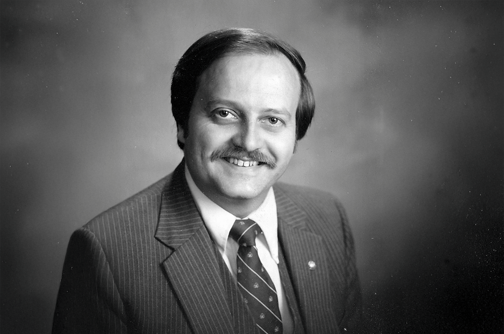 Black and white photo of man in suit and tie smiling