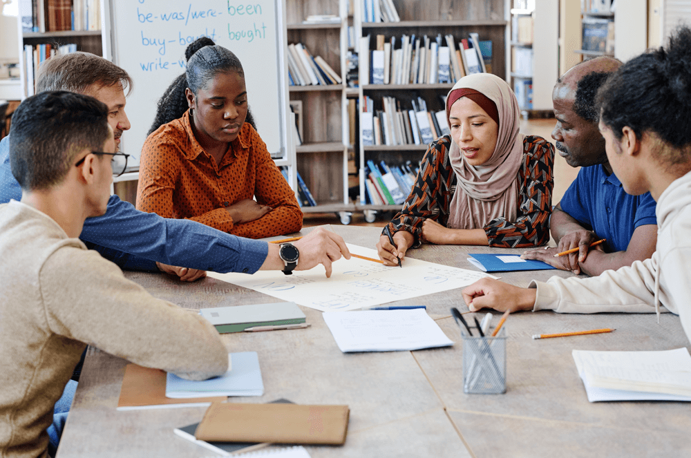 Group of people sitting at a table looking at a paper