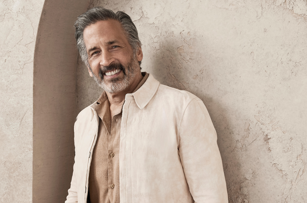 Bill Hernandez Man standing in linen jacket leaning against a wall