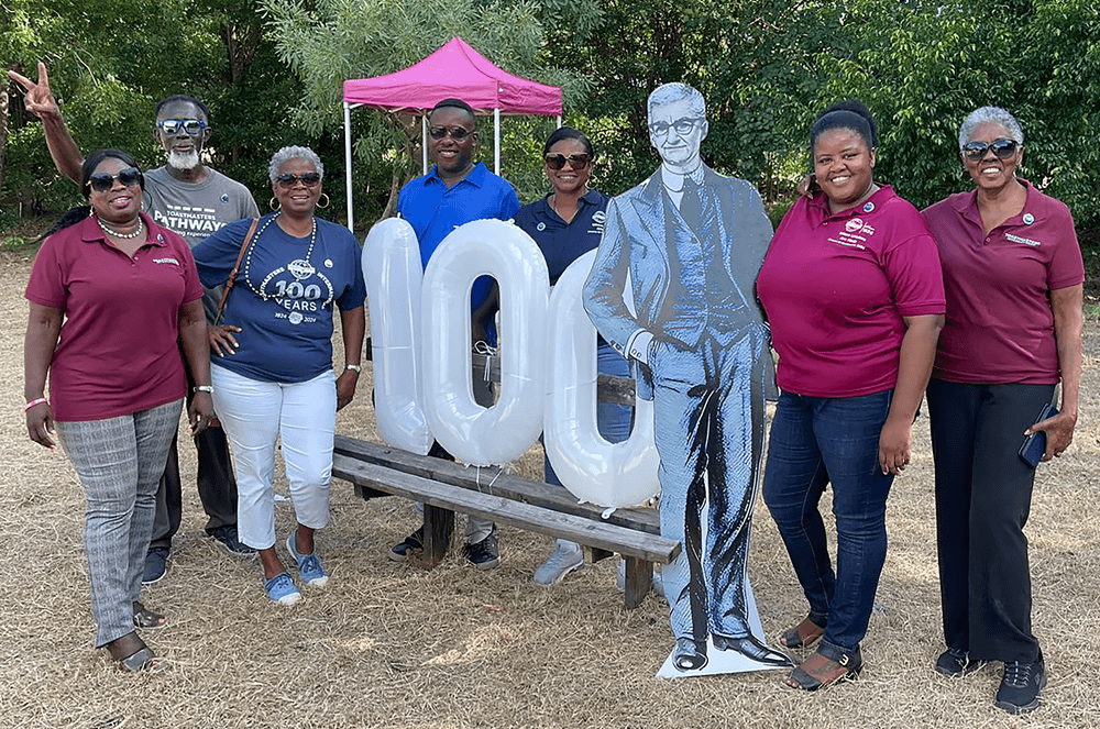 A group of people standing next to balloons and a cutout of Dr. Ralph C. Smedley