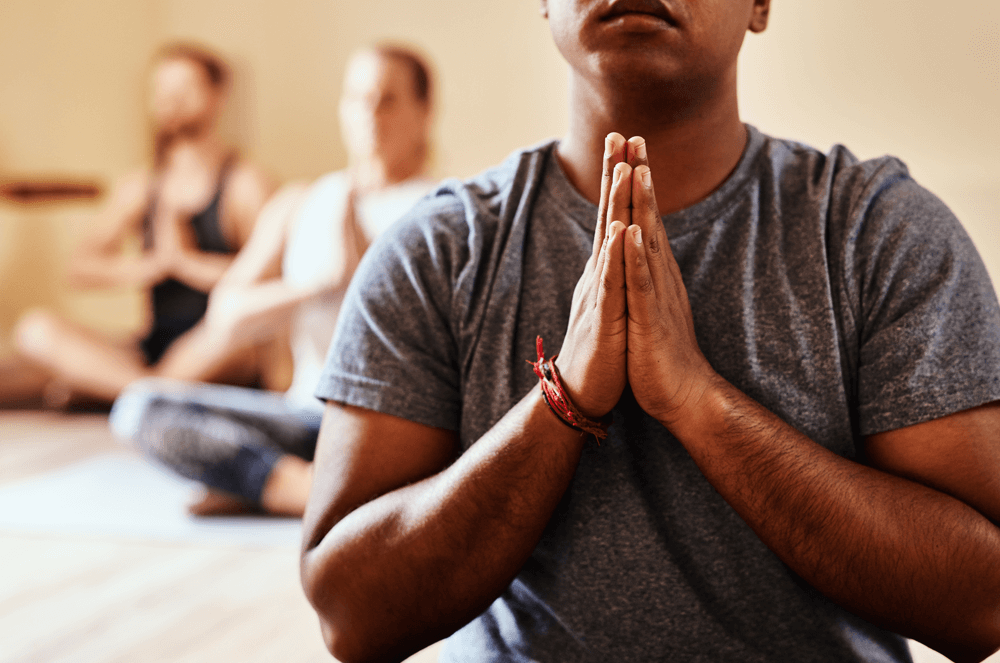 Group of people sitting cross-legged with hands raised