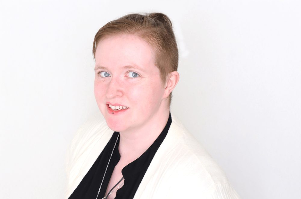 Person in black shirt and white suit jacket smiling