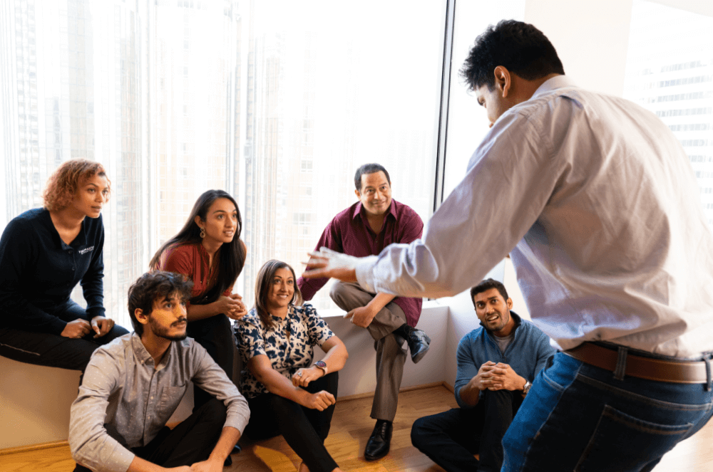 A man with his arms raised speaking to a group of people