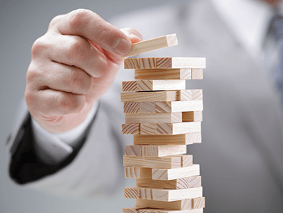 Hand setting wooden block on Jenga pile