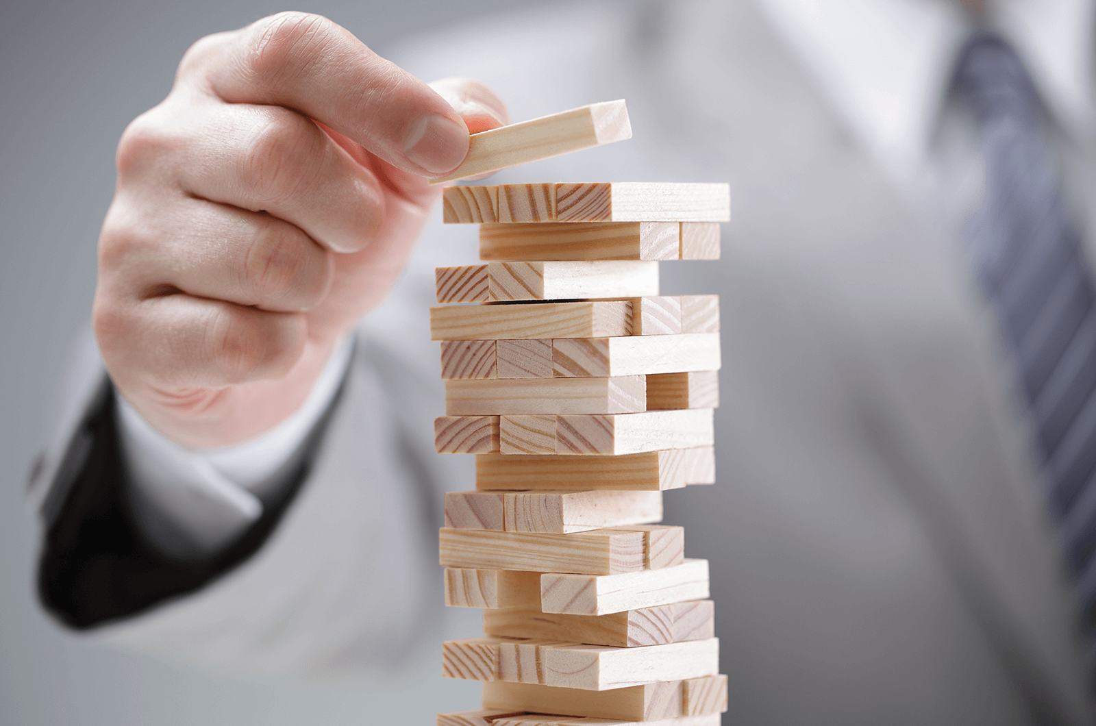 Hand setting wooden block on Jenga pile