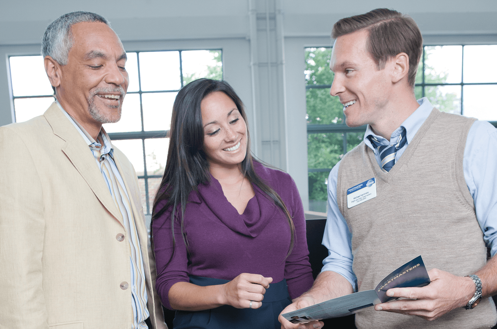 Two men speak with woman in middle