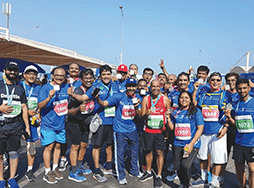 Members of Khimji Toastmasters in blue shirts pose after running Muscat Marathon 