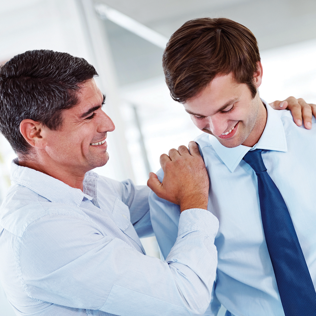 Man showing empathy with hands on male co-worker's shoulders