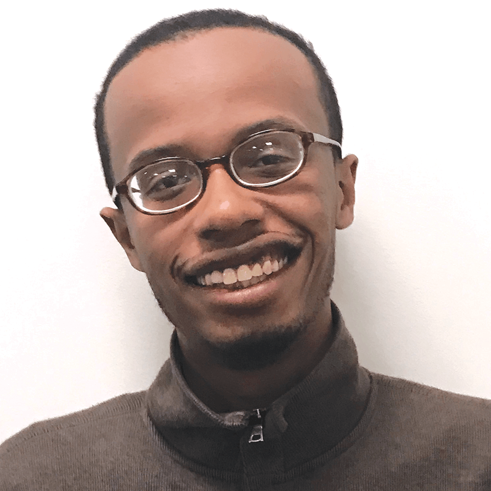 Man in brown shirt and glasses smiles