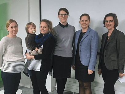 Five female members and a baby pose at a club meeting