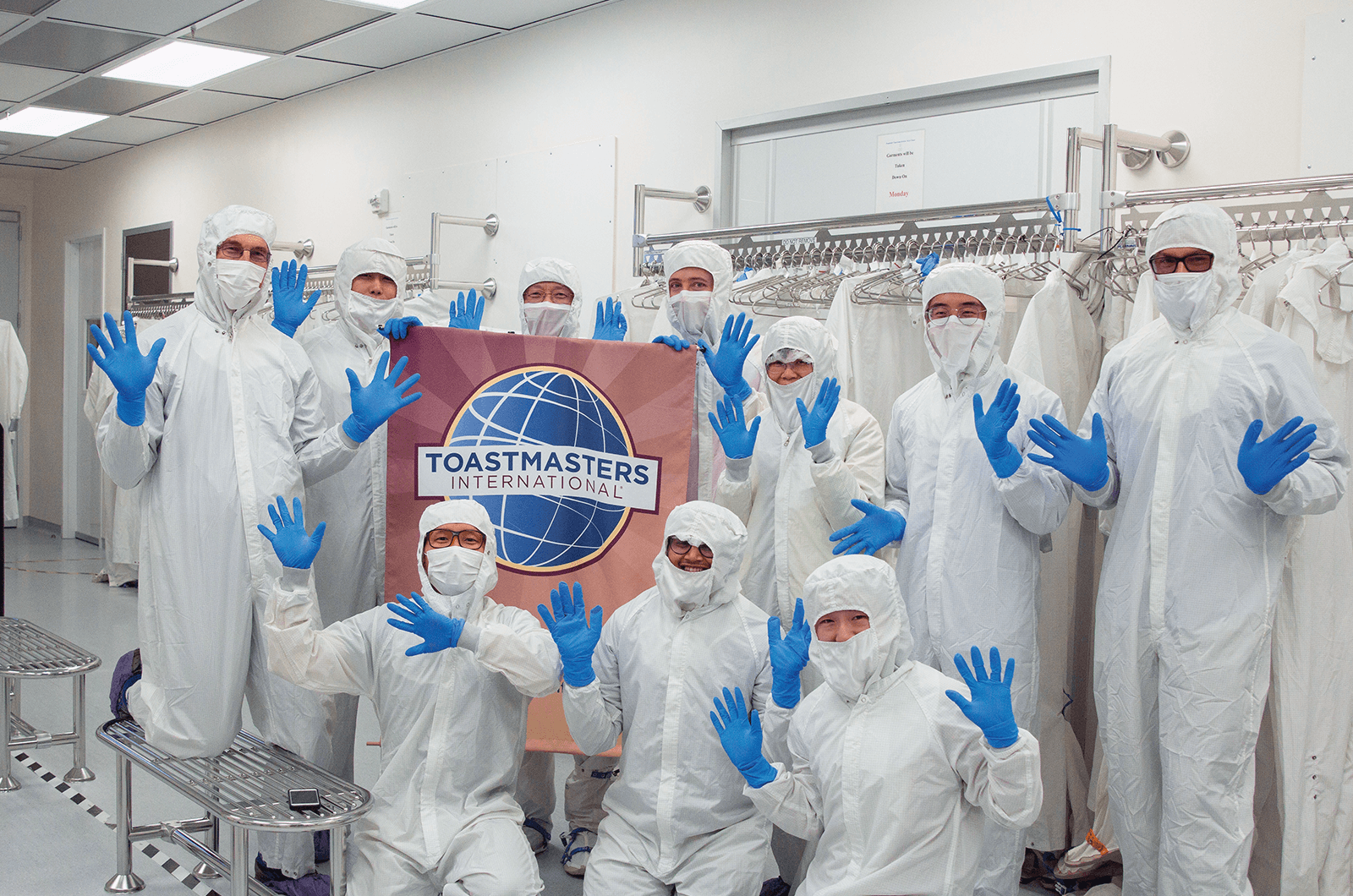 Group of Toastmasters dressed in white suits and blue masks in cleaning room