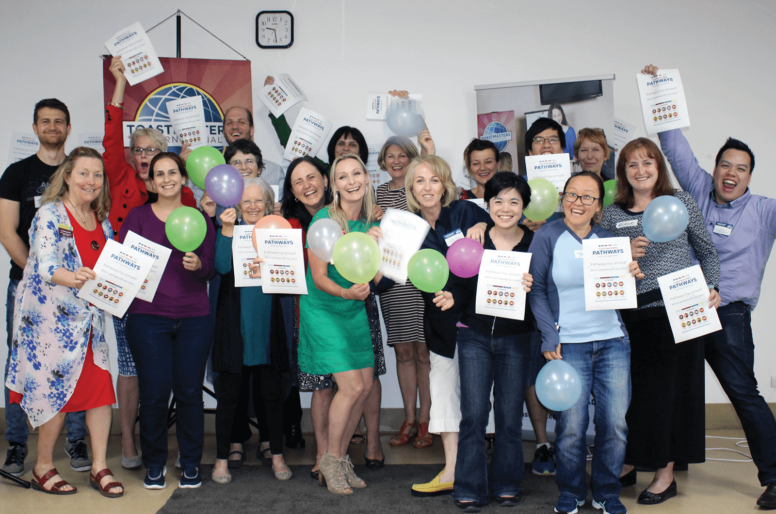 Group of Toastmasters members holding balloons and signs