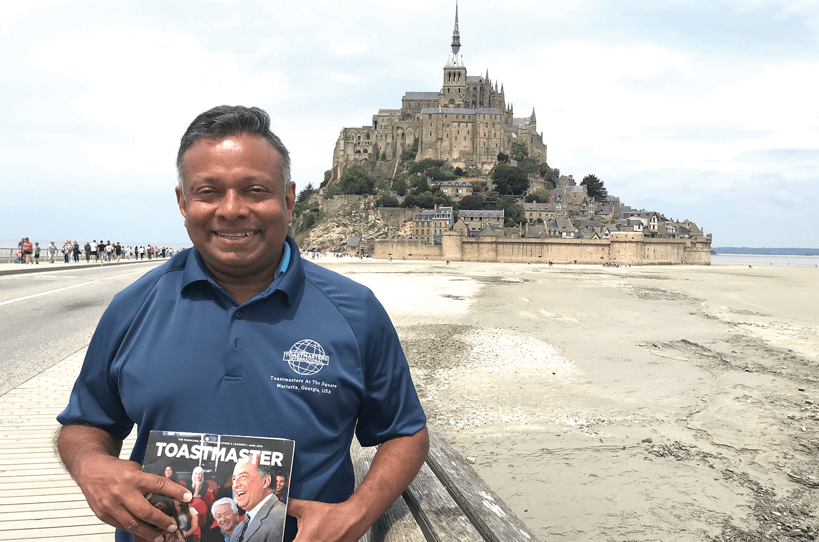Manuja Ranasinghe, DTM, of Roswell, Georgia, poses in front of the Abbey at Mont-Saint-Michel—an island connected to Normandy, France. 