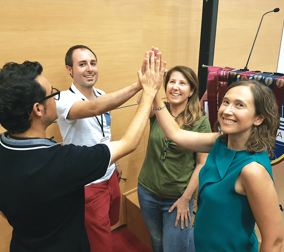 Four people in circle high-fiving