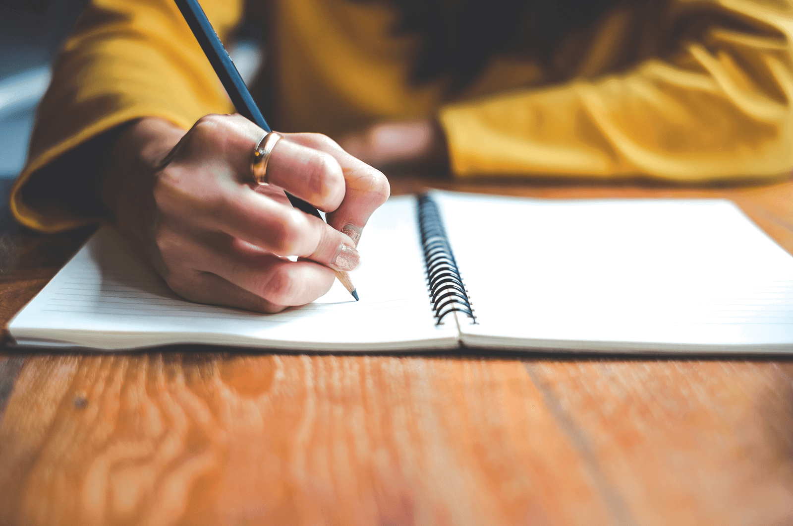 Person writing with a pencil in a notebook