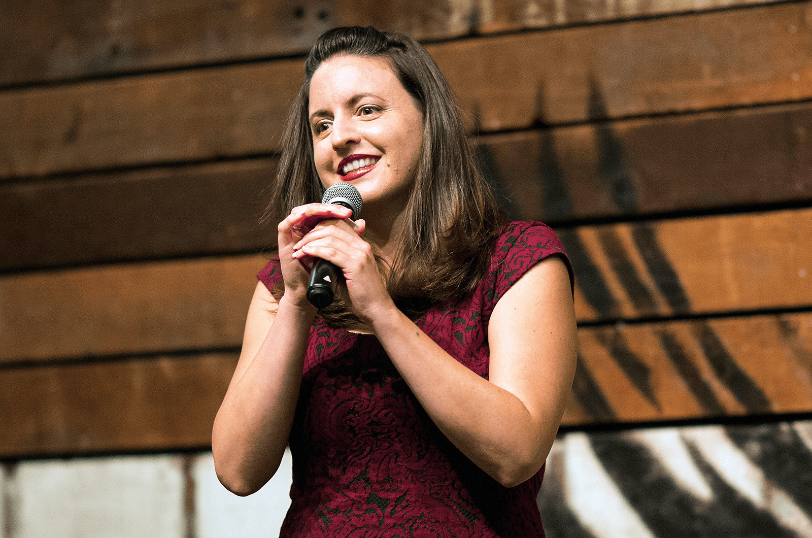 Woman in red dress onstage holding microphone