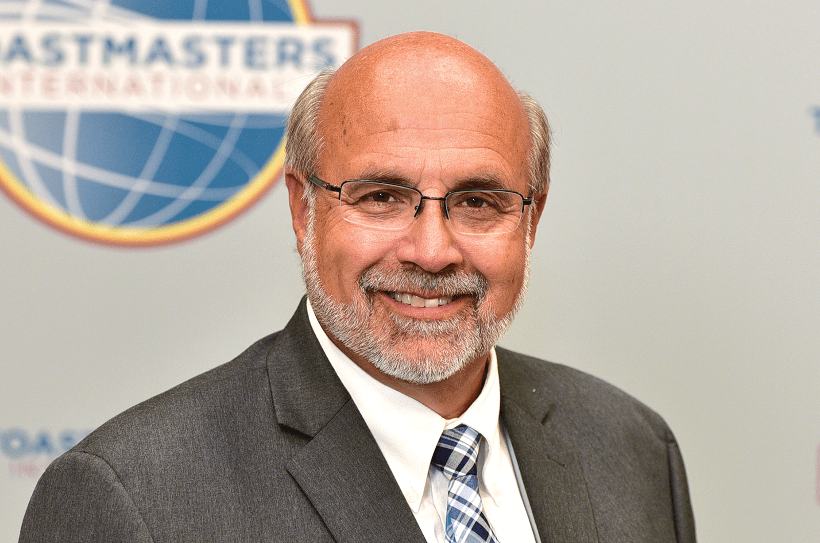 Man in gray jacket and tie smiling