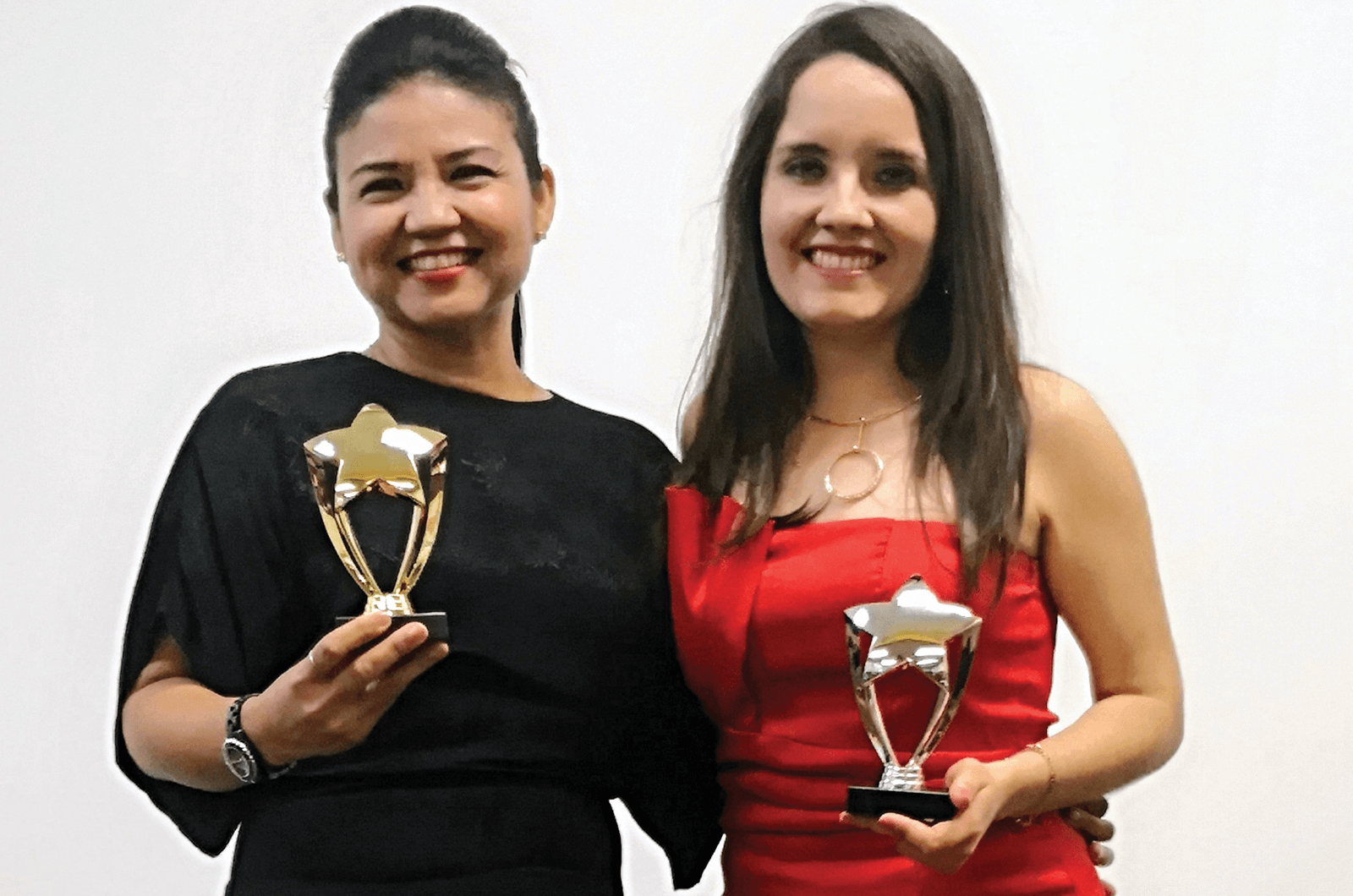 Two women in dresses holding trophies