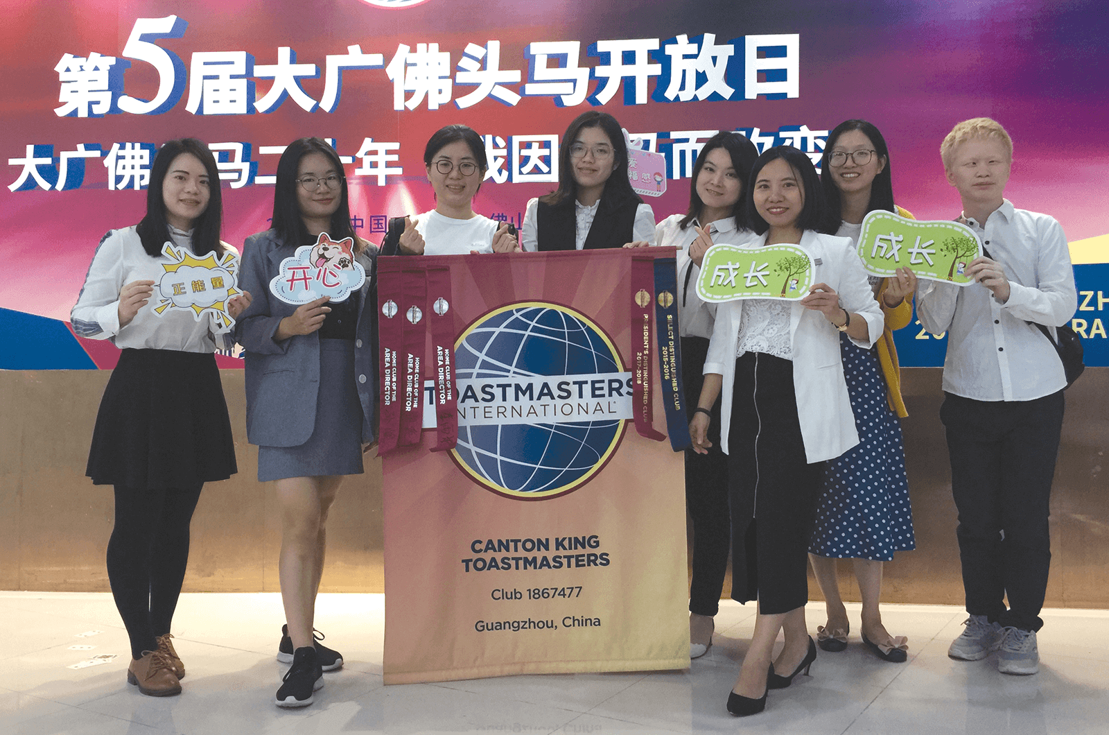 Group of Toastmasters holding club banner and signs