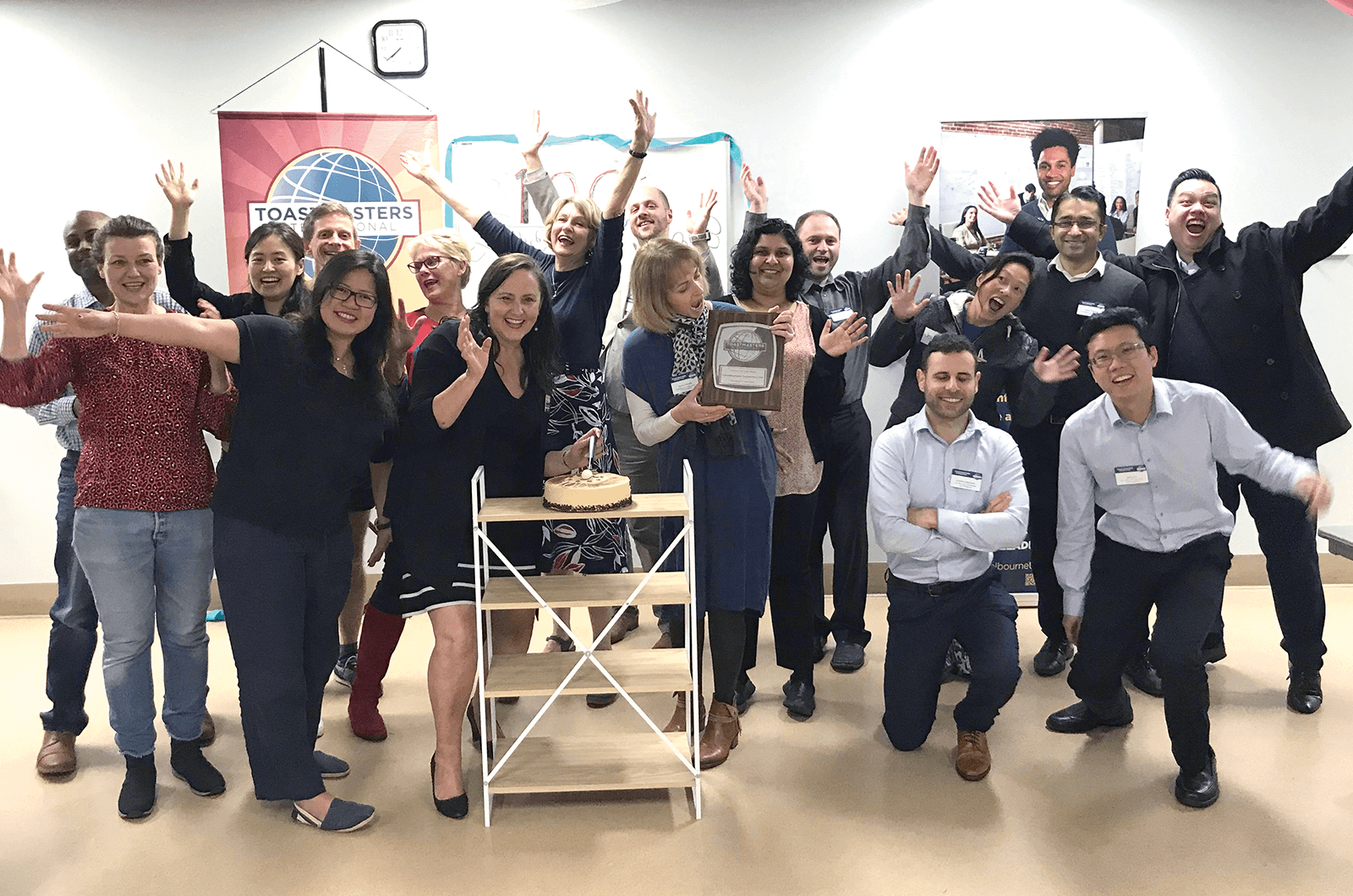 Group of Toastmasters members posing with banner