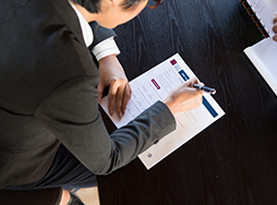 Person filling out form with pen