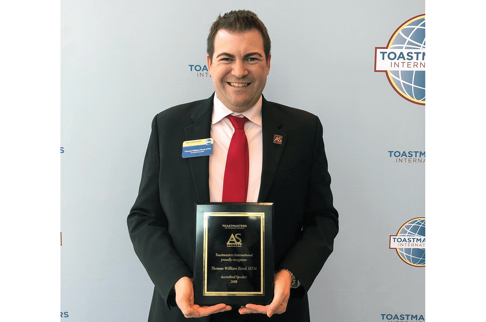 Thomas Iland poses with Toastmasters plaque