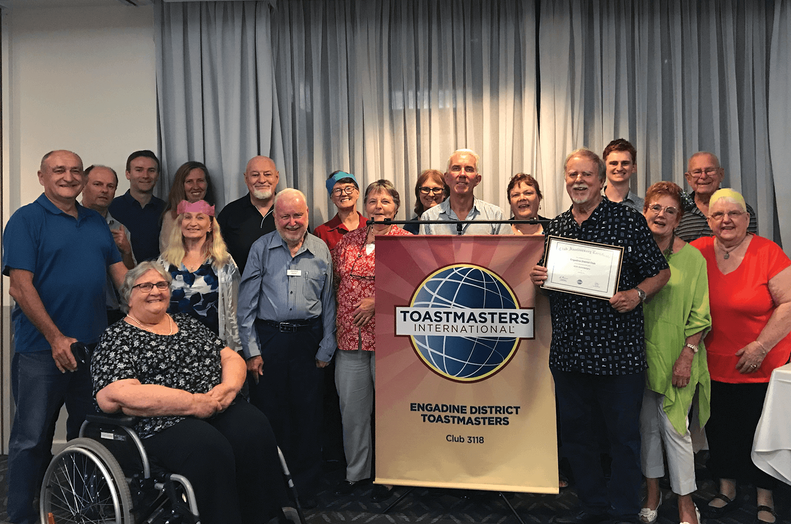 Group of Toastmasters members posing with banner