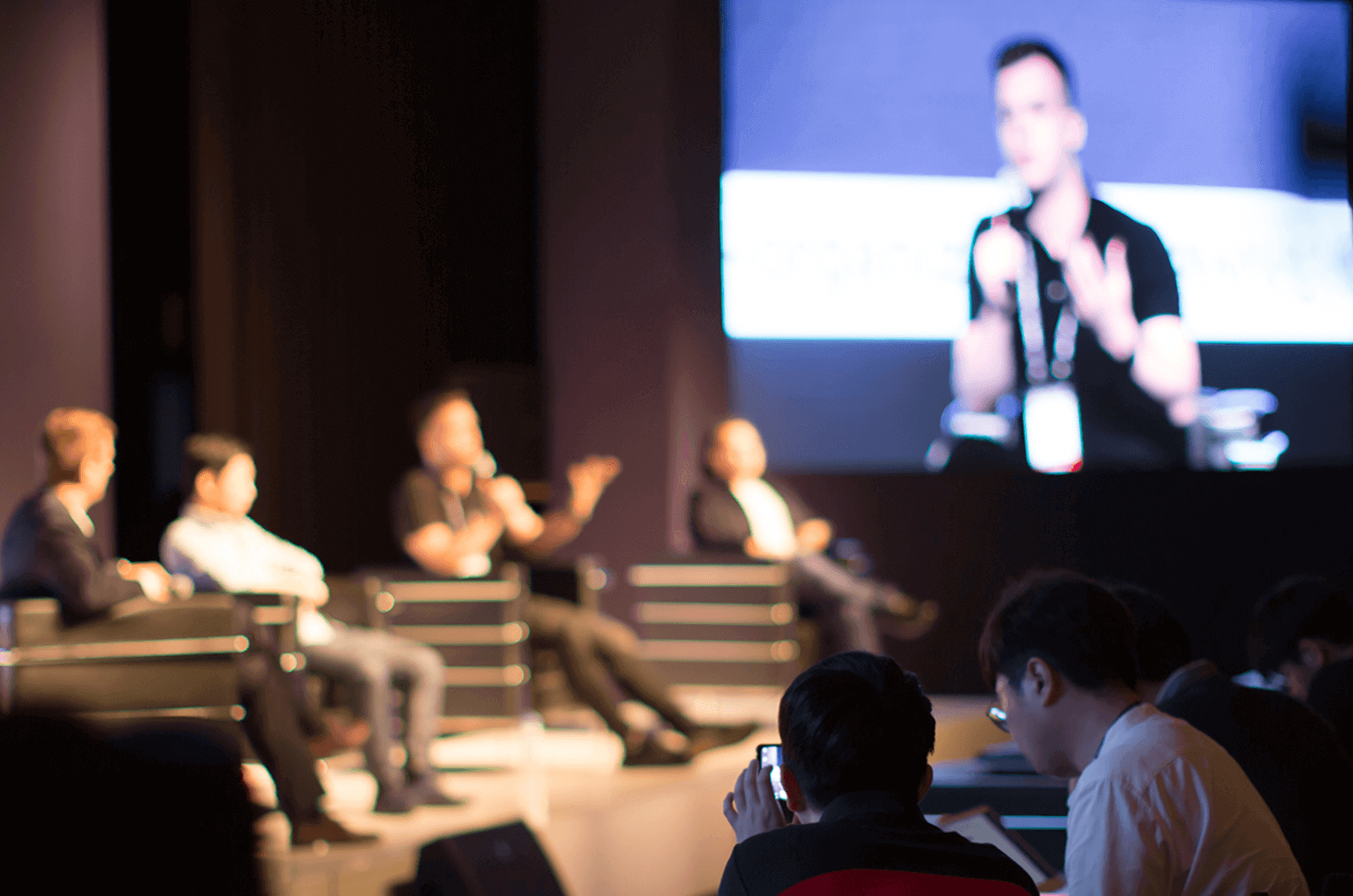 People sitting in chairs on a stage during panel discussion  