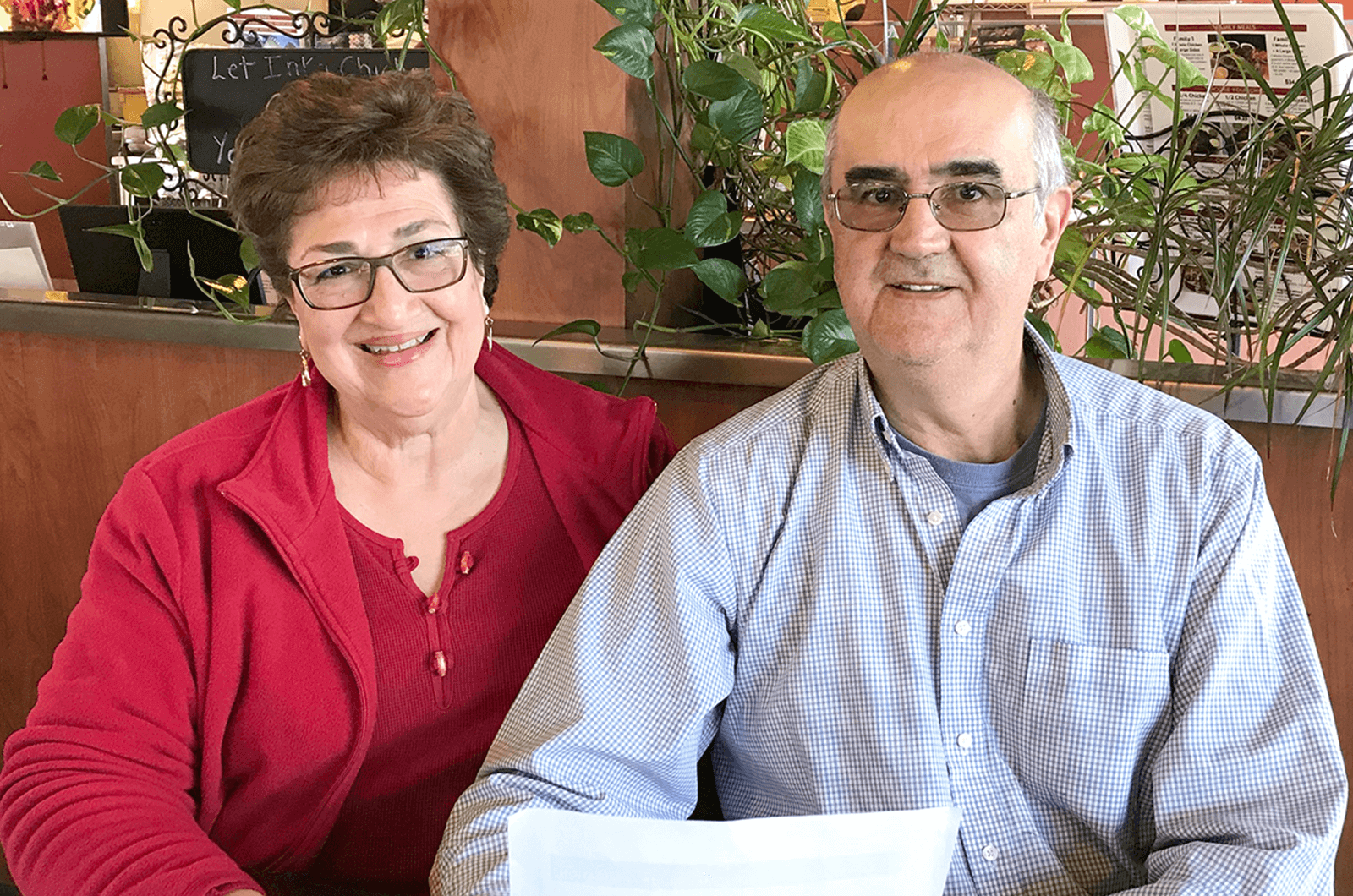 Woman in red jacket sitting next to her husband in booth