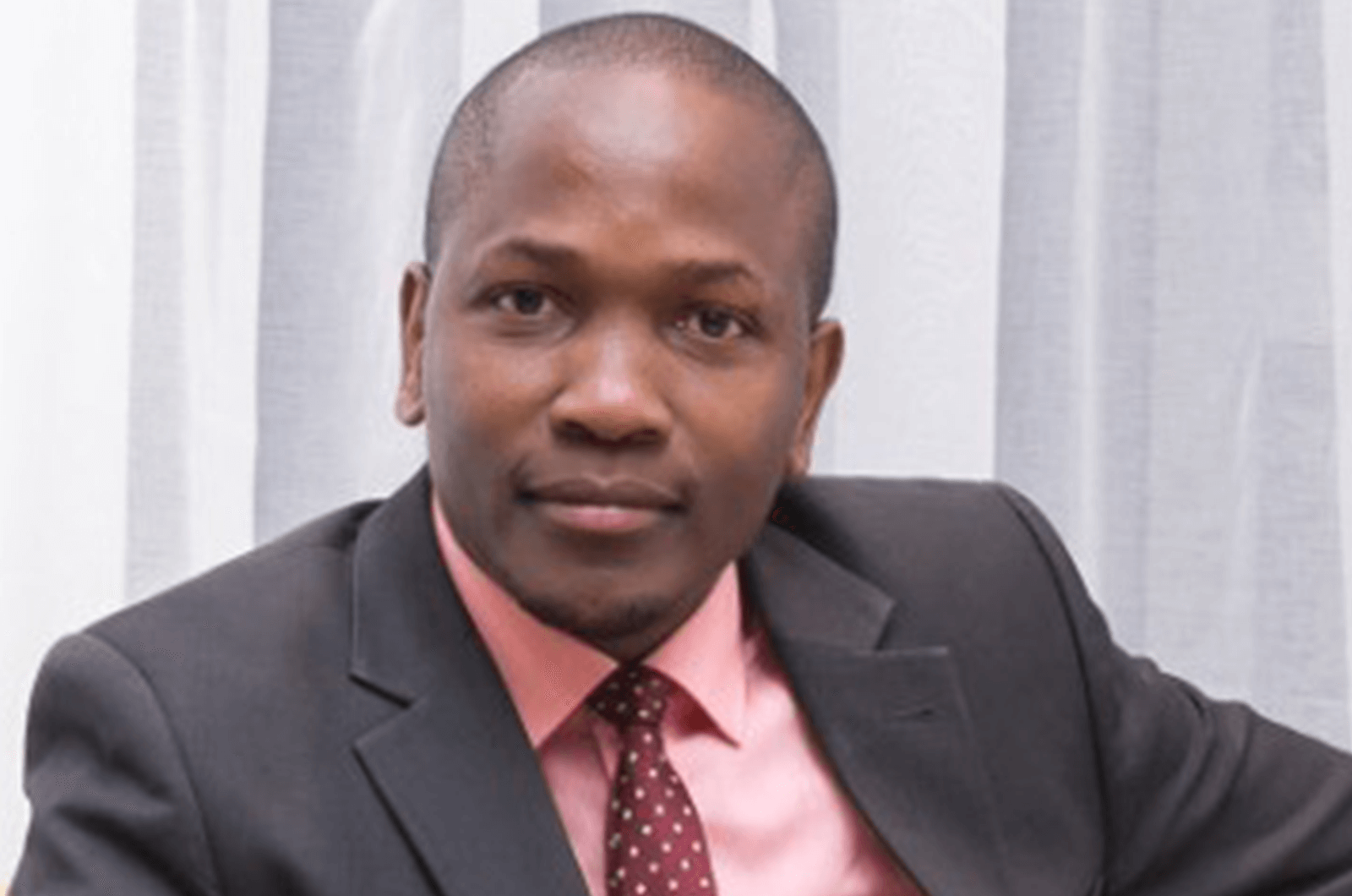 Robert Kimani in suit jacket and tie smiling for headshot