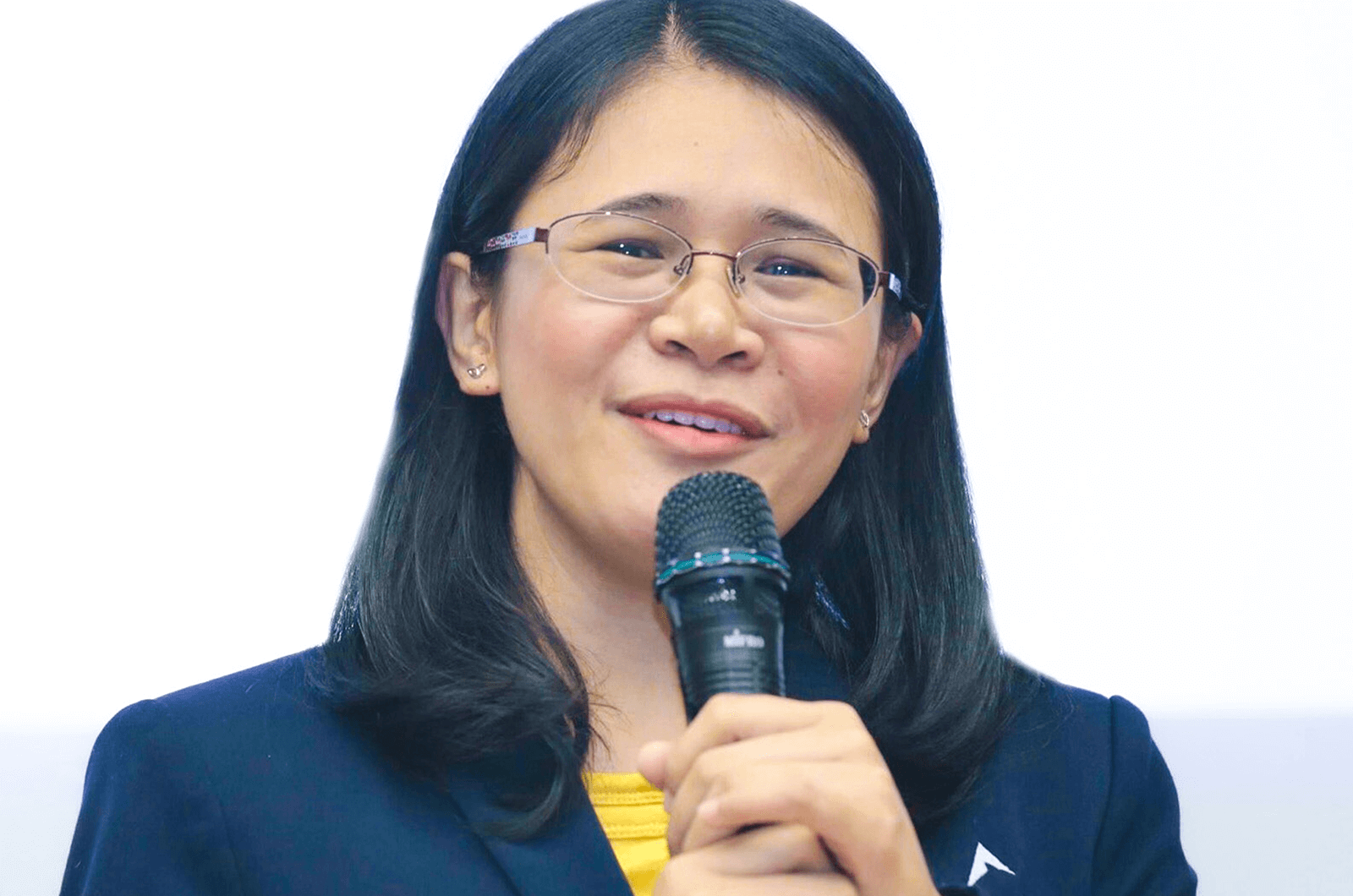 Woman in blue jacket speaking into microphone