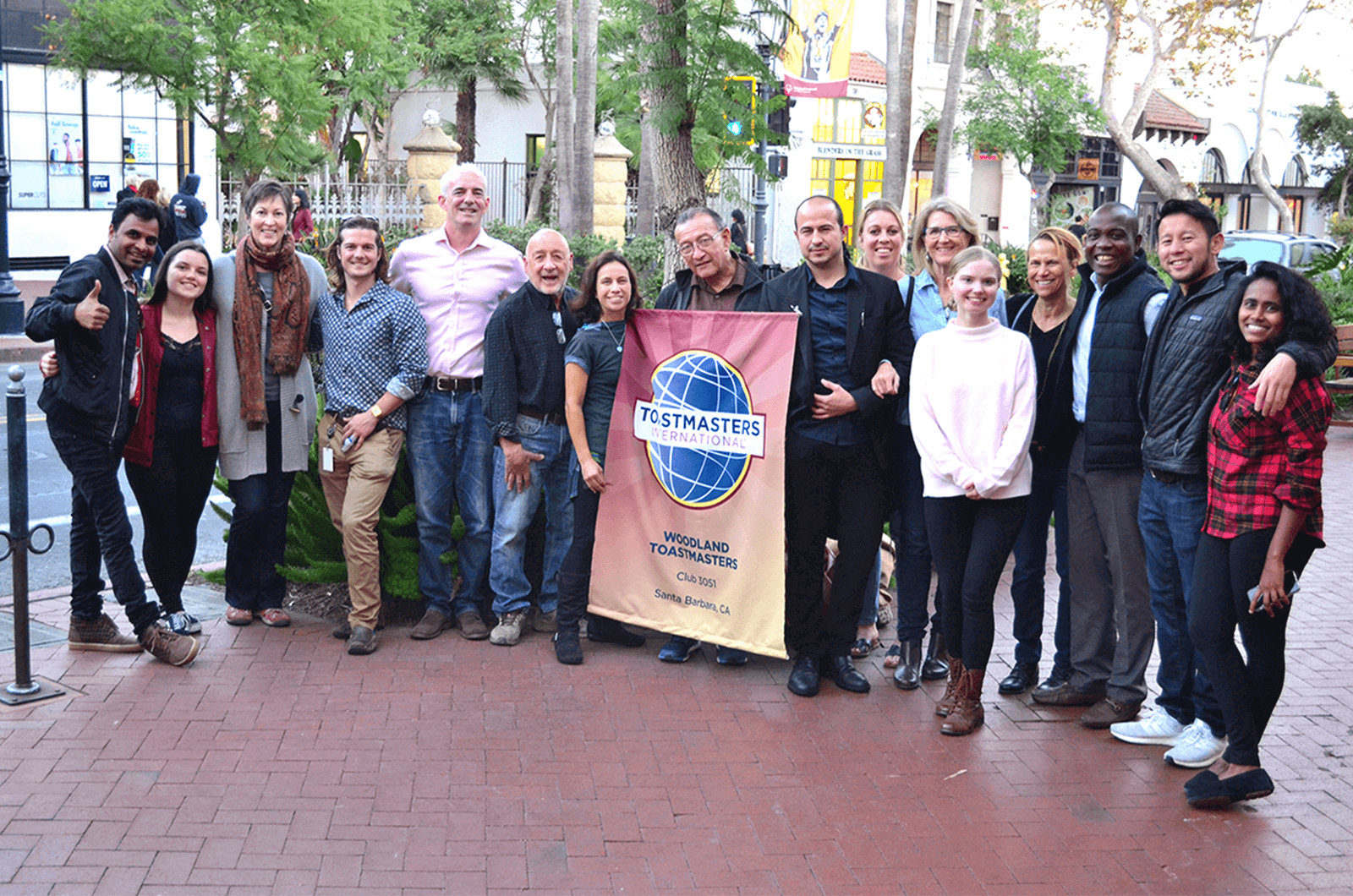 Group of people standing outside holding up banner