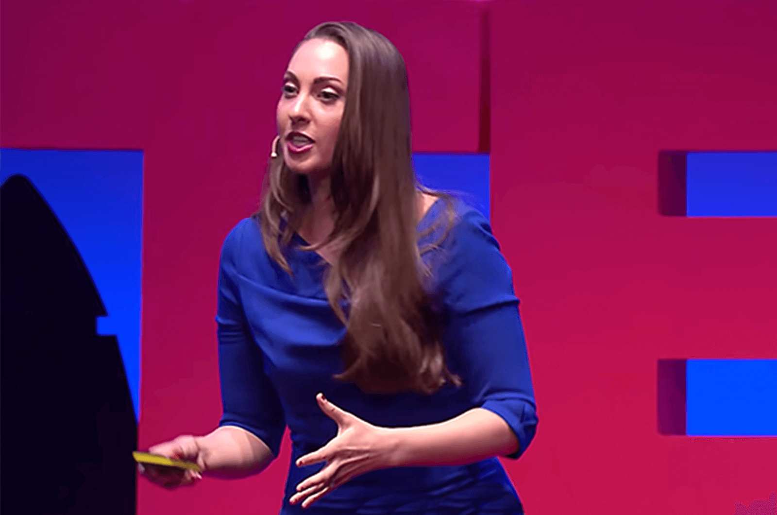 Woman in blue dress speaking onstage.