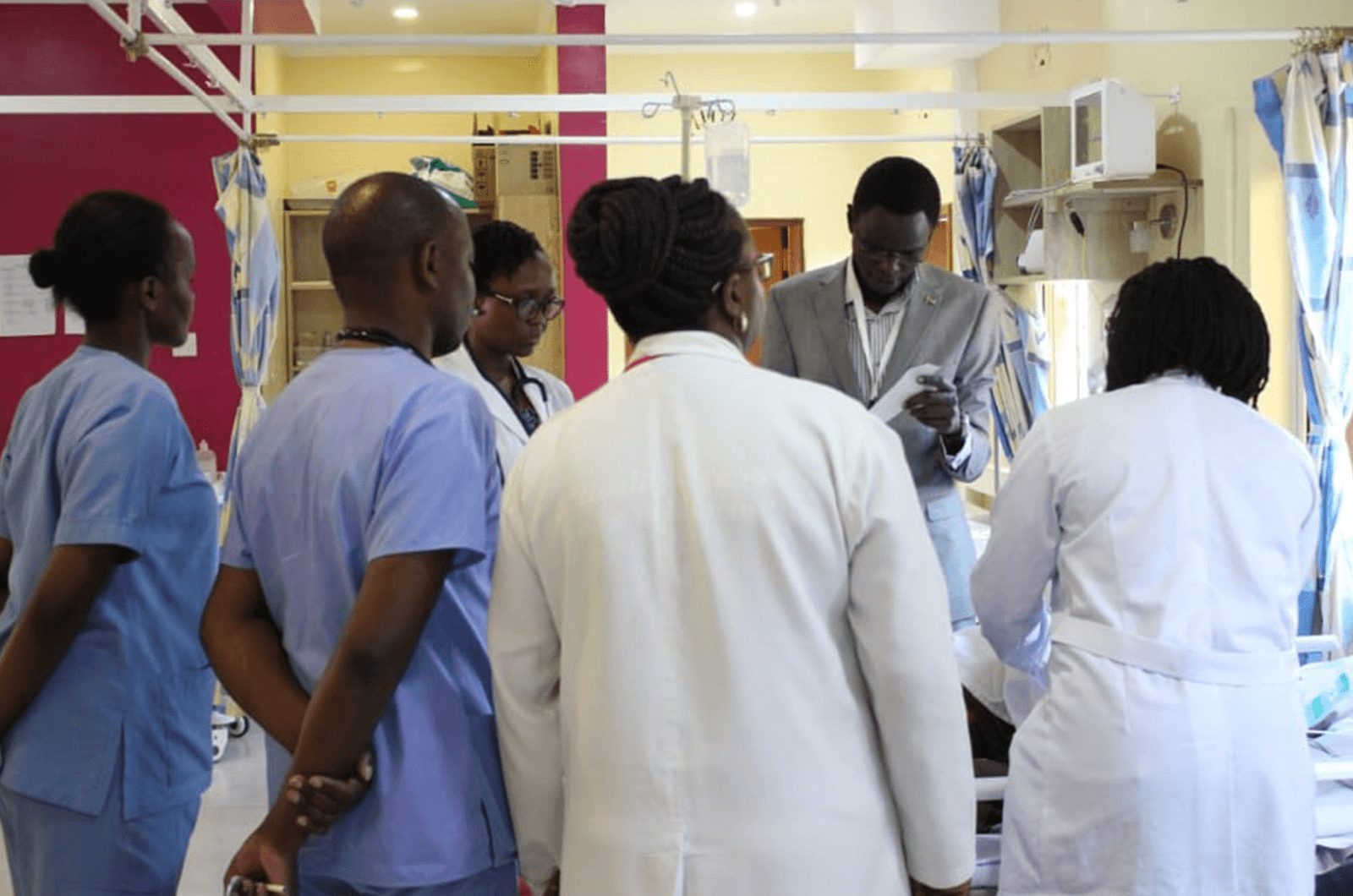 Medical staff in a hospital stand around doctor listening 