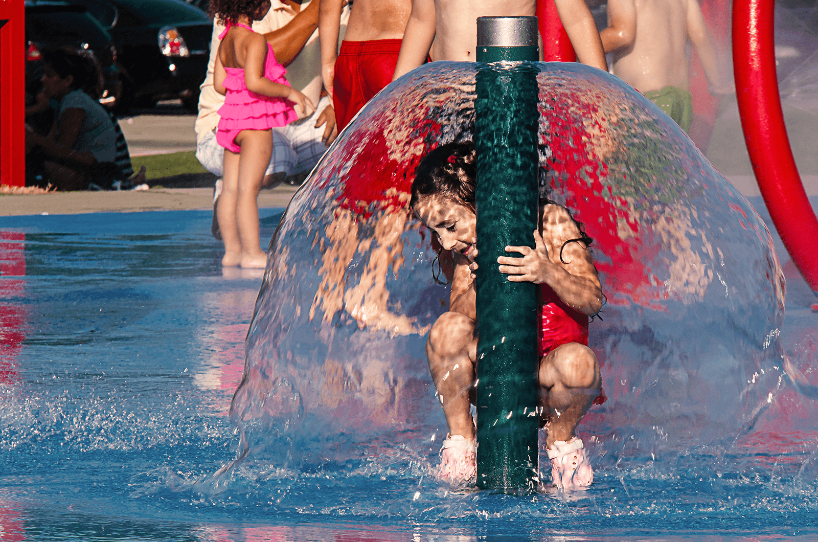 Little girl under umbrella of water at park