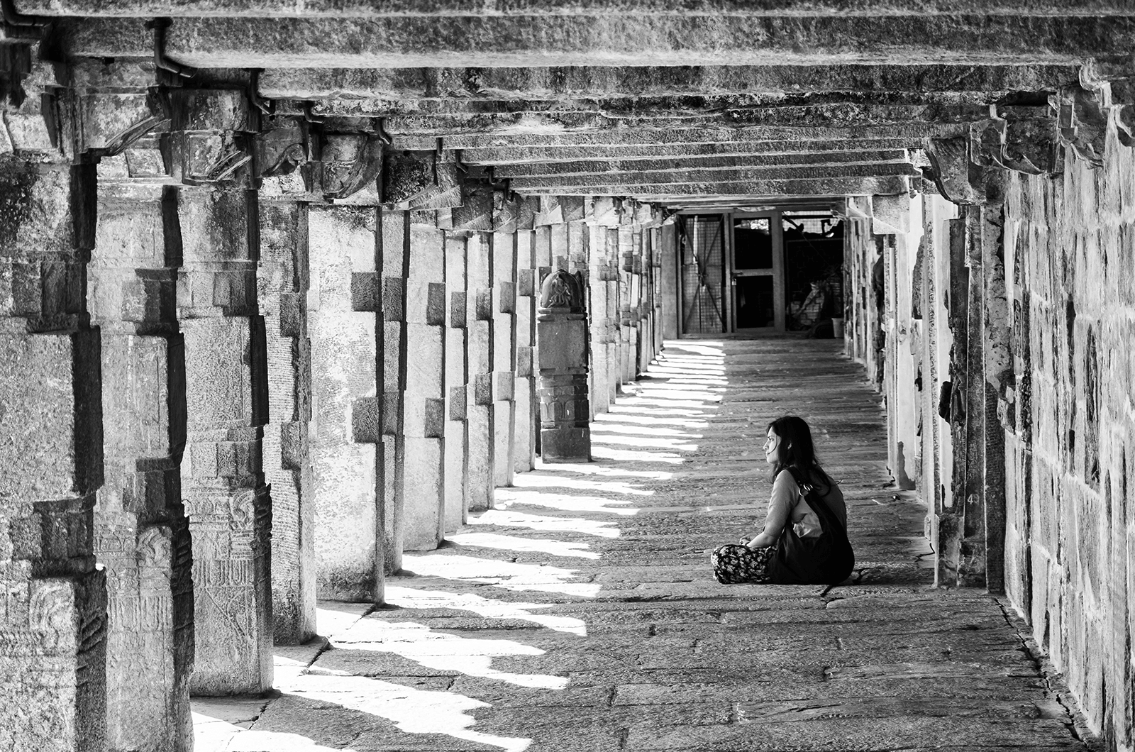 Black and white photo of woman sitting in temple in India